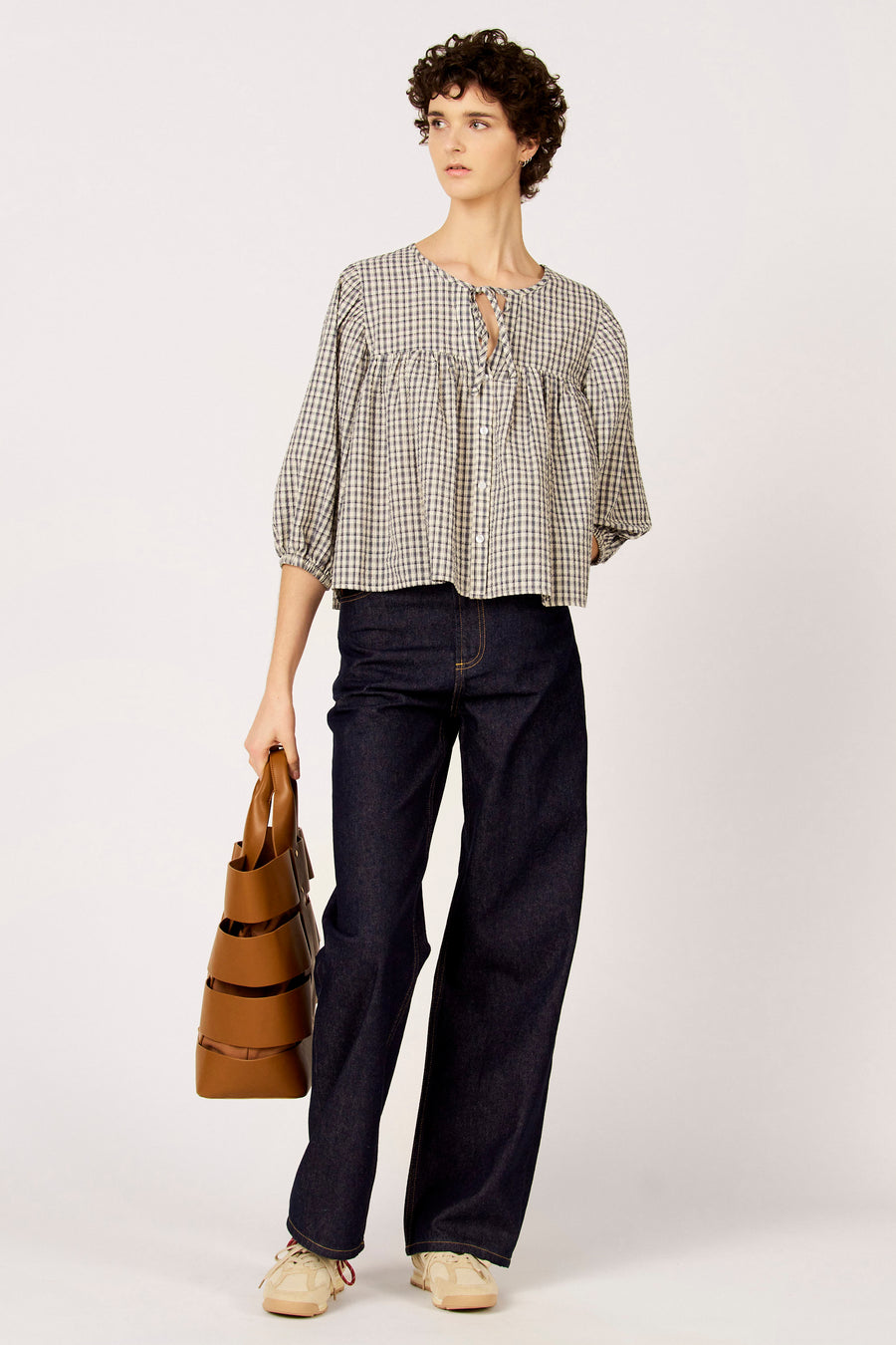 Blauw blouse met driekwart mouwen van Le Fabuleux Marcel de Bruxelles, met ruitpatroon en gedragen met donkere jeans en beige sneakers.