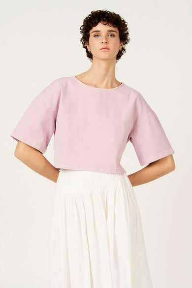 Chemisier rose à manches courtes de Le Fabuleux Marcel de Bruxelles, avec une coupe courte et une jupe blanche.