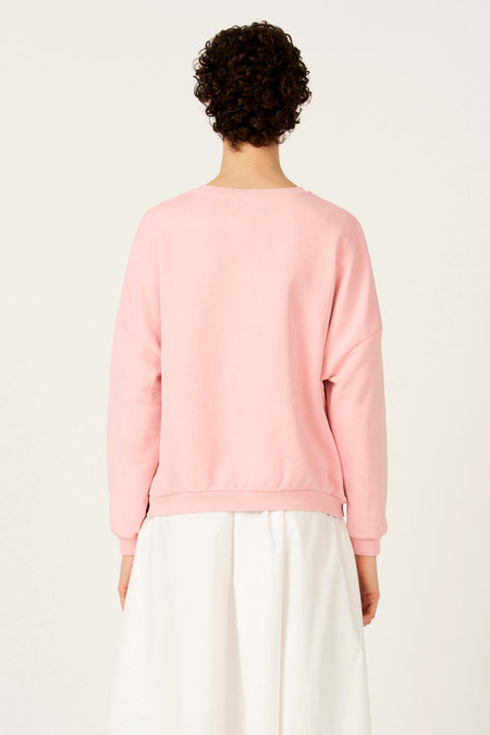 Roze sweater met ronde hals van Le Fabuleux Marcel de Bruxelles, rugaanzicht met witte rok.
