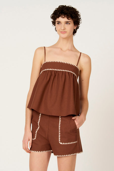Bruine blouse zonder mouwen van Le Fabuleux Marcel de Bruxelles, met broderie details langs de randen, gedragen met bijpassende shorts.
