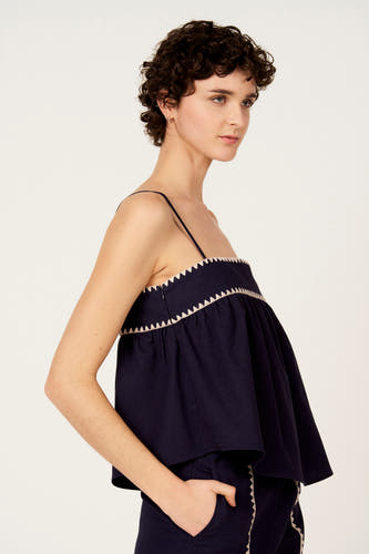 Blauwe blouse zonder mouwen van Le Fabuleux Marcel de Bruxelles, met decoratieve zigzag rand, gedragen met bijpassende broek.