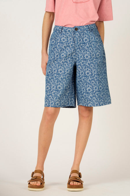 Denim bermuda van Le Fabuleux Marcel de Bruxelles met bloemenprint en bruine sandalen.
