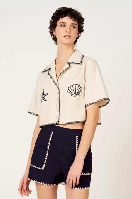 Ecru hemd met korte mouwen van Le Fabuleux Marcel de Bruxelles, met nautische applicaties en donkerblauwe zigzagstiksels.