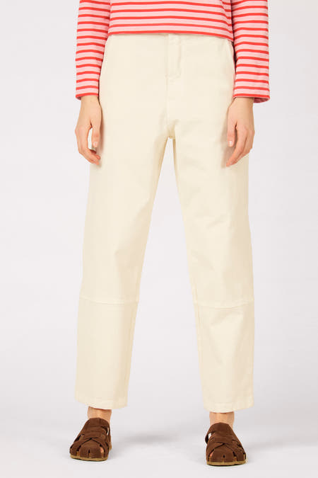 Pantalon écru de Le Fabuleux Marcel de Bruxelles, avec poche arrière et un haut à rayures roses et rouges.