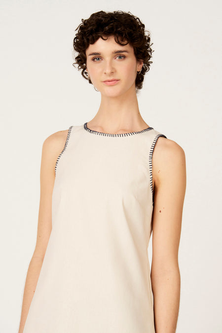 Robe écru sans manches de Le Fabuleux Marcel de Bruxelles, avec coutures bleues le long de l'encolure et des emmanchures.