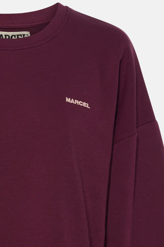 Description détaillée du pull violet à col rond de Le Fabuleux Marcel de Bruxelles, avec 'MARCEL' brodé sur la poitrine.