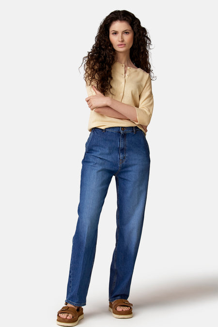 Slim-fit donkerdenim jeans van Le Fabuleux Marcel de Bruxelles, gecombineerd met een geel vest en bruine sandalen.