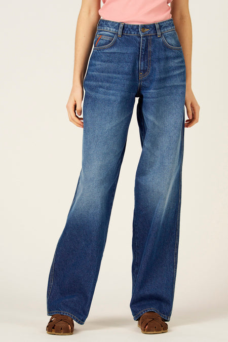 Wijd uitlopende jeans van medium blauw denim van Le Fabuleux Marcel de Bruxelles, met lichte wassing en bruine sandalen.
