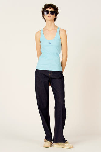 Wijde denim jeans van Le Fabuleux Marcel de Bruxelles, gecombineerd met een blauw hemdje, zonnebril en crèmekleurige schoenen.