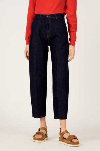 Jeans slim de couleur denim bleu foncé, de Le Fabuleux Marcel de Bruxelles, combinés avec des sandales marron et un pull rouge, vue de côté.