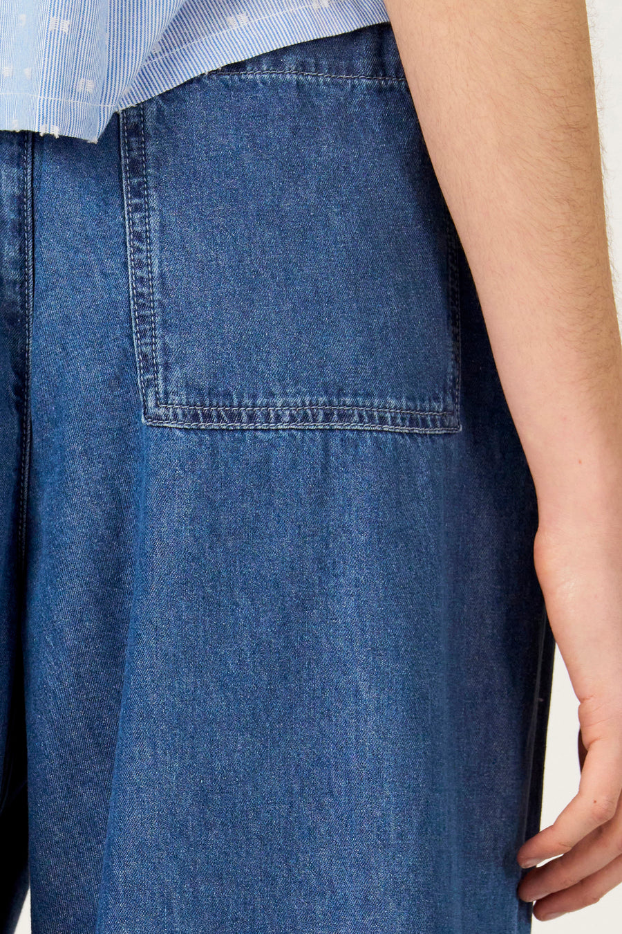 Wijde jeans van blauw denim van Le Fabuleux Marcel de Bruxelles, met opgestikte zak, gecombineerd met een gestreept overhemd.

