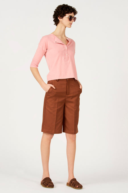 Bruine bermuda van Le Fabuleux Marcel de Bruxelles, gedragen met een roze shirt en bruine sandalen.