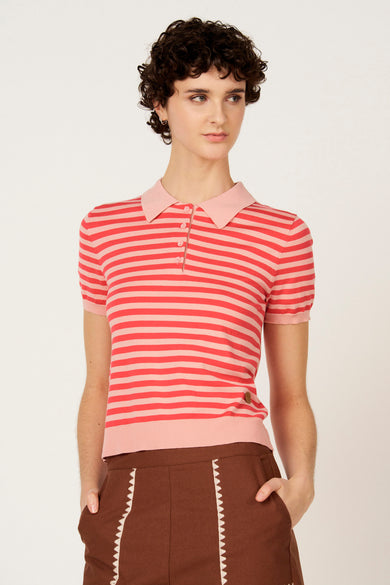 Rode trui met ronde hals van Le Fabuleux Marcel de Bruxelles, met horizontale strepen en bruine broek met witte details.
