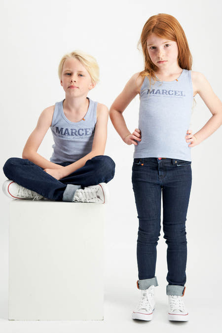T-shirt bleu de Le Fabuleux Marcel de Bruxelles, porté par des enfants avec des jeans et des baskets blanches.