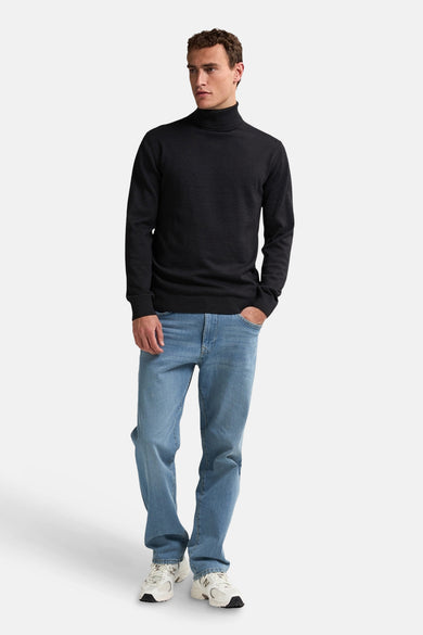 Zwarte trui met rolkraag van Petrol Industries, gedragen met jeans en witte sneakers.
