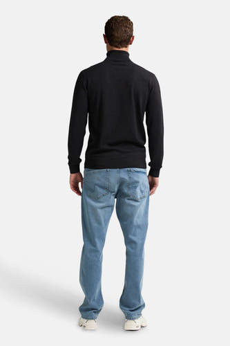 Pull noir avec col montant de Petrol Industries, vu de dos, avec des jeans légers et des baskets blanches.