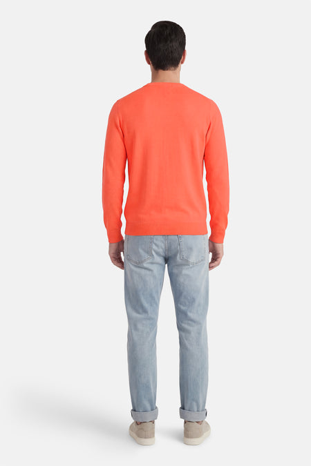 Koraalkleurige trui met ronde hals van Petrol Industries, gezien van achteren, gecombineerd met een lichtblauwe jeans en crèmekleurige sneakers.