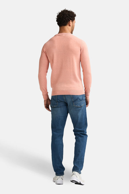 Roze trui met ronde hals van Petrol Industries, rugaanzicht, gecombineerd met jeans en witte sneakers.