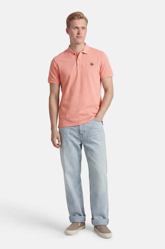 Roze polo met korte mouwen van Petrol Industries®, met logo op de borst, gecombineerd met jeans en schoenen.
