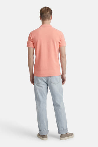 Roze polo met korte mouwen van Petrol Industries, gezien van achteren, met een lichtblauwe jeans en beige schoenen.