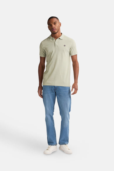Groene polo met korte mouwen van Petrol Industries®, met een klein logo op de borst, gecombineerd met blauwe jeans en witte sneakers.
