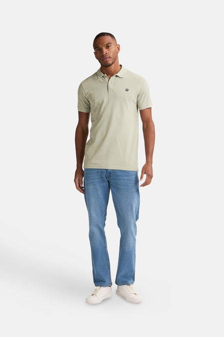 Groene polo met korte mouwen van Petrol Industries®, met een klein logo op de borst, gecombineerd met blauwe jeans en witte sneakers.
