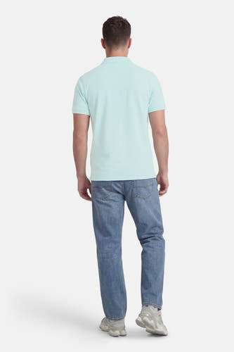 Groene polo met korte mouwen van Petrol Industries, gedragen met jeans en grijze sneakers, van achteren gezien.