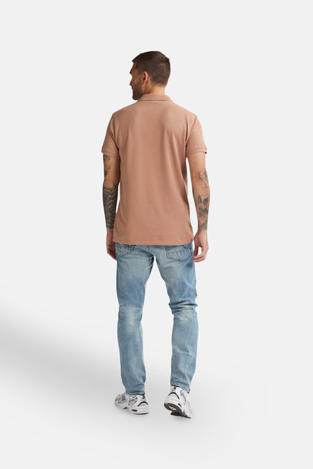 Polo marron à manches courtes de Petrol Industries®, vu de l'arrière, porté avec des jeans et des baskets.