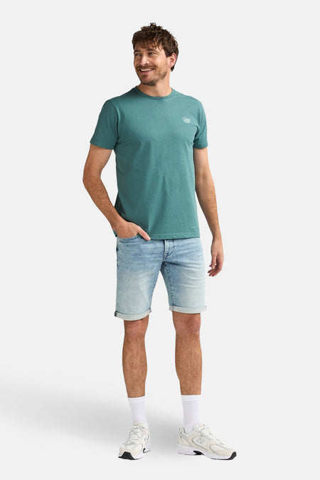 Short en jean denim bleu clair de Petrol Industries® avec ourlets retroussés, combiné avec un t-shirt vert et des baskets blanches.