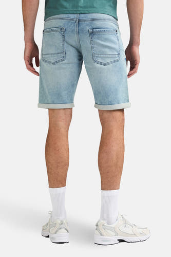 Lichtblauwe denim jeansshort van Petrol Industries®, achterkant met zakken en opgerolde pijpen, gecombineerd met witte sokken en sneakers.
