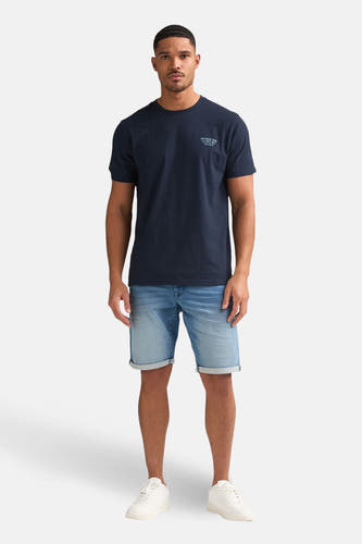 Blauwe jeansshort van Petrol Industries, gecombineerd met een donkerblauw T-shirt en witte sneakers.