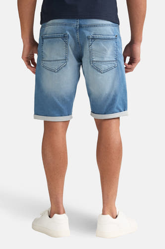 Blauwe jeansshort van Petrol Industries, gezien van achteren, met opgerolde pijpen en witte sneakers.
