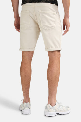Ecru short van Petrol Industries, achterkant, met opgerolde zomen, gestyled met een donker T-shirt en witte sneakers.