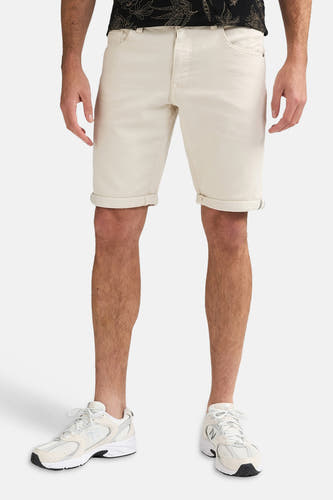Ecru short van Petrol Industries met omgeslagen zomen, gedragen door een man met een donker shirt en witte sneakers.
