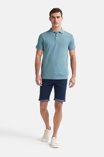 Donkerblauwe short van Petrol Industries met omgeslagen zoom, gecombineerd met een blauw polo shirt en witte sneakers.
