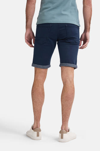 Donkerblauwe short van Petrol Industries, achterkant, met opgerolde pijpen en beige sneakers.