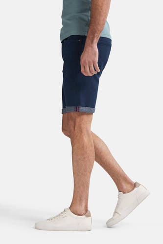 Donkerblauwe short van Petrol Industries met opgerolde pijpen en witte sneakers, in zij-aanzicht.