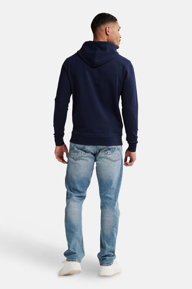 Blauwe sweater met kap van Petrol Industries®, achterkant, gecombineerd met lichte jeans en witte sneakers.
