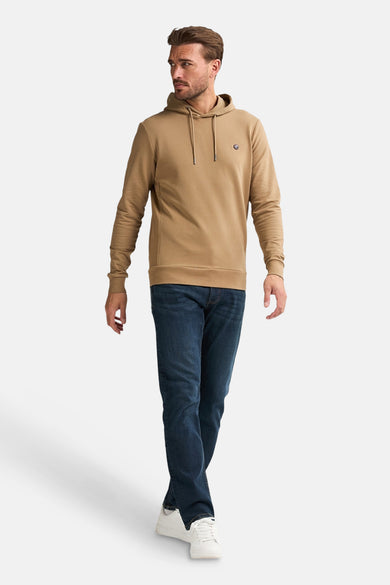 Ecru sweater met kap van Petrol Industries, gedragen met een donkerblauwe jeans en witte sneakers.
