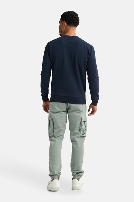 Sweater bleu de Petrol Industries® avec des manches longues, porté avec des pantalons cargo verts et des baskets blanches, vue arrière.