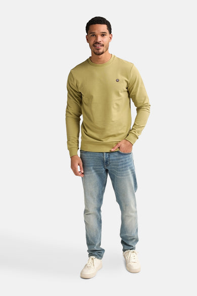 Groene sweater van Petrol Industries® gedragen met een blauwe jeans en witte sneakers.
