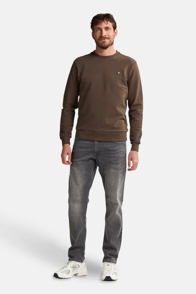 Bruine sweater van Petrol Industries met een ronde hals, gecombineerd met een grijze jeans en witte sneakers.