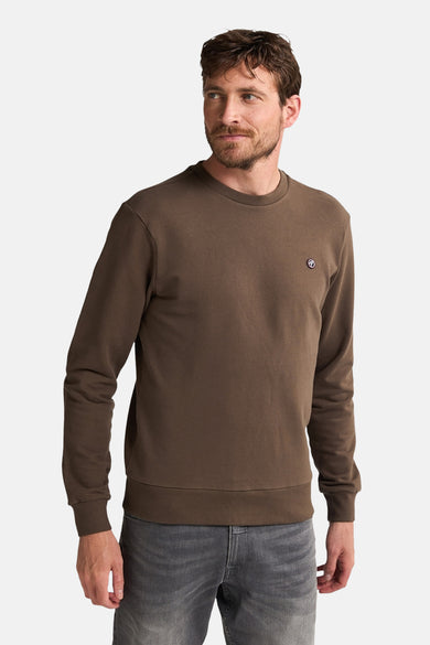 Bruine sweater van Petrol Industries® met ronde hals en klein logo op de borst, gecombineerd met grijze jeans.
