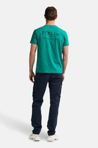 Pantalon cargo bleu de Petrol Industries avec poches latérales, porté avec un t-shirt vert et des baskets blanches.