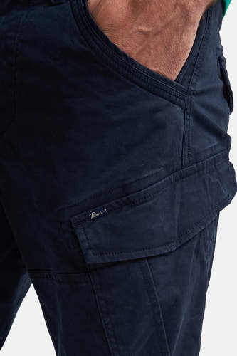 Pantalon de travail bleu de Petrol Industries, avec poche sur la jambe et main dans la poche.