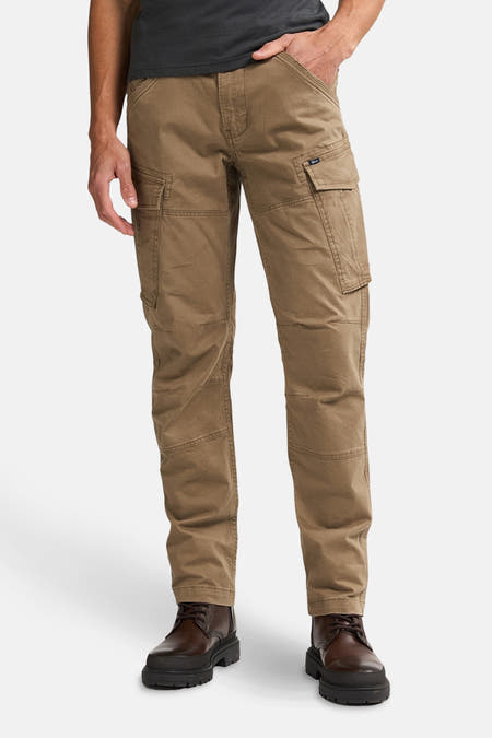 Pantalon cargo écru de Petrol Industries, porté avec un t-shirt gris à imprimé graphique sur le dos et des chaussures marron foncé.