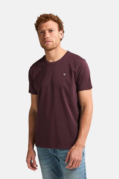 Bordeaux T-shirt met korte mouwen van Petrol Industries, met een klein logo op de borst en gedragen met een jeans.
