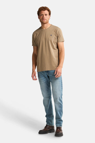 T-shirt écru à manches courtes de Petrol Industries, porté avec des jeans bleus et des bottes marrons.