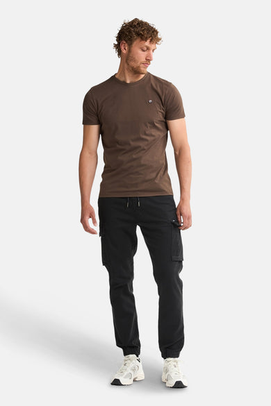 Bruin T-shirt met korte mouwen van Petrol Industries, met een klein logo op de borst en gedragen met een zwarte cargobroek.
