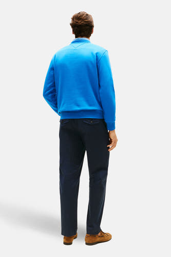 Blauwe sweater met ronde hals van TOMMY HILFIGER, rugzijde, gecombineerd met donkere broek en bruine schoenen.
